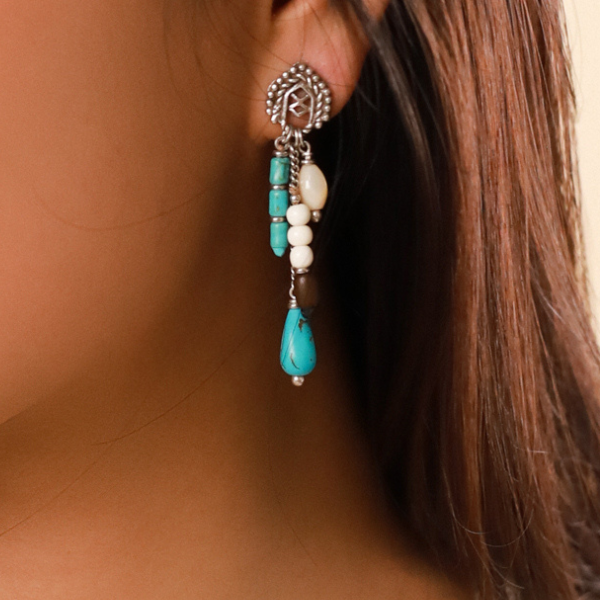 Image of model wearing silver post earrings with long dangles embellished with semi precious beads and stones in aqua and cream and brown.