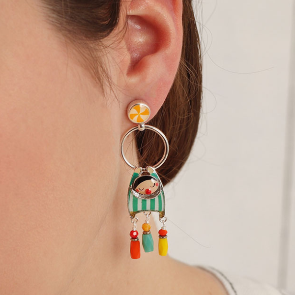 Image of model wearing hand painted trapeze act characters on round dangle earrings.