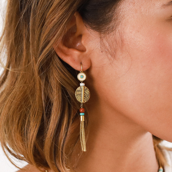 Image of model wearing ethnic style earrings with long chain tassel dangle with red and aqua beads on french hook.