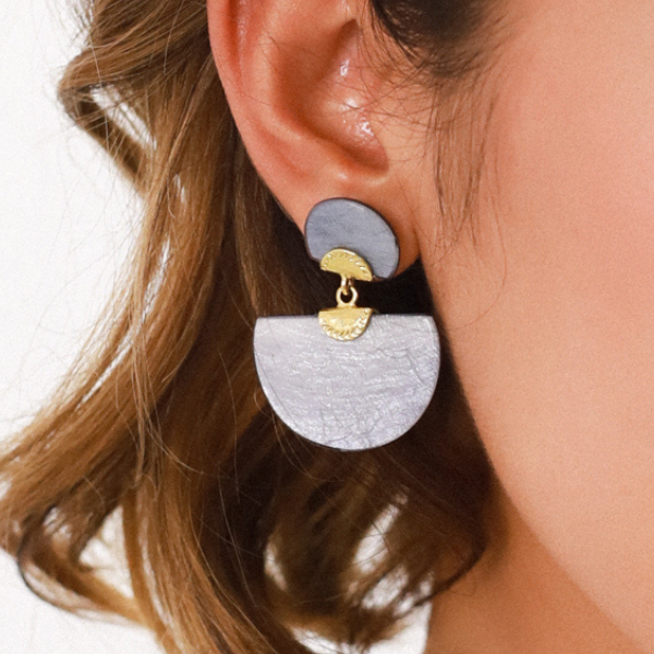 Image of model wearing dyed capiz blue post earrings with half circle dangle.