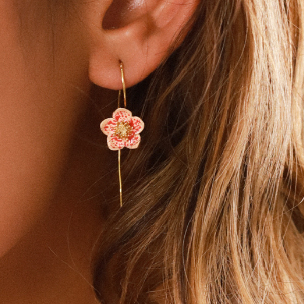 Image of model wearing dainty flower drop earrings in pink and white on long gold hook.