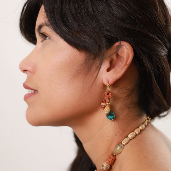Image of model wearing hoop dangle earrings created from turquoise, seed pods and beads.