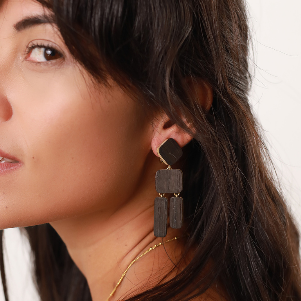 Image of model wearing dangle earrings with geometric pieces of lightweight wood.