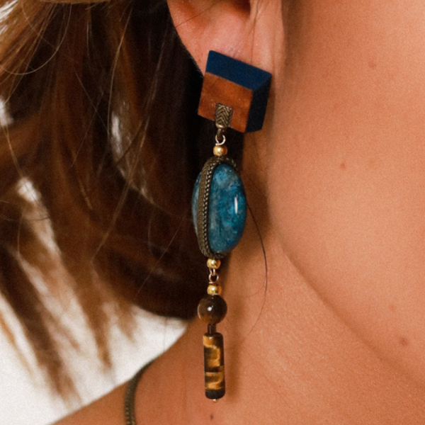 Image of model wearing square wood veneer earrings with long dangle of apatite stone and tiger eye.
