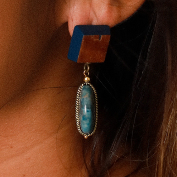 Image of model wearing wood veneer square earrings with round blue apatite dangle.