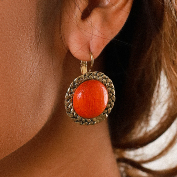 Image of round earrings with papaya inspired orange centre edged with a rusty gold metal.