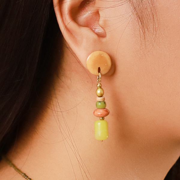 Image of round model wearing post earrings with semi precious stone dangles in green, beige and salmon.