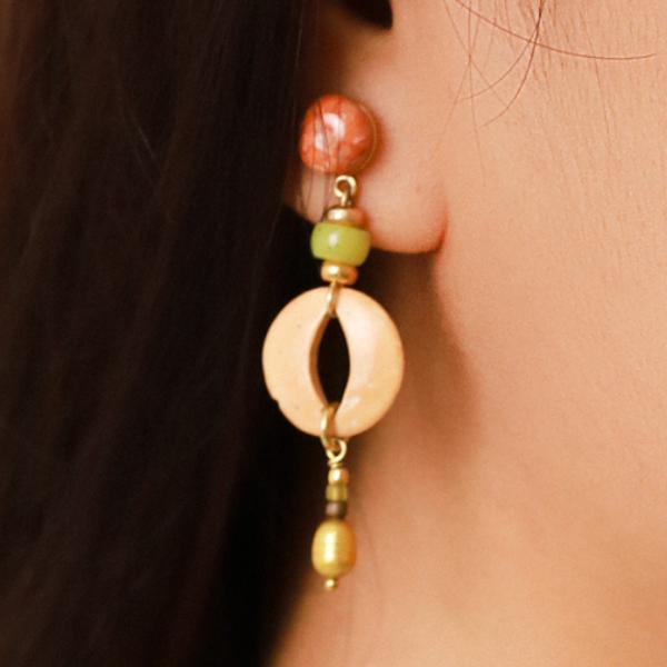 Image of model wearing semi precious stones dangle earrings in green, red, salmon and beige on gold plated finish.