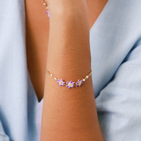 Image of model wearing dainty gold metal bracelet with 3 lilac flowers centrepiece.