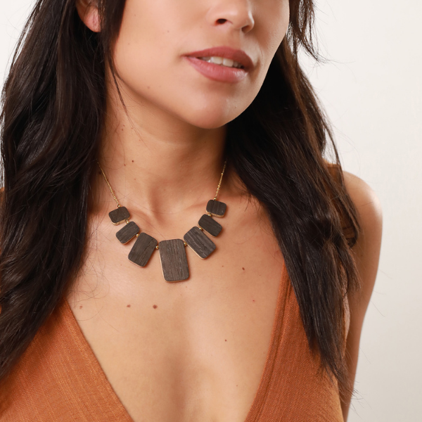 Image of model wearing contemporary, geometric necklace crafted from dark chocolate timber and gold gilded chain.