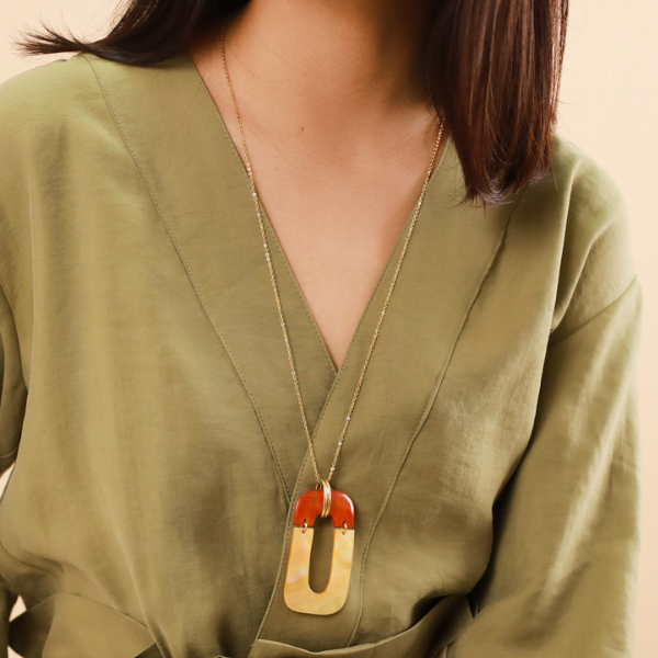 Image of model wearing big rectangle necklace made from golden mother-of-pearl and jackfruit wood on gold plated finish.
