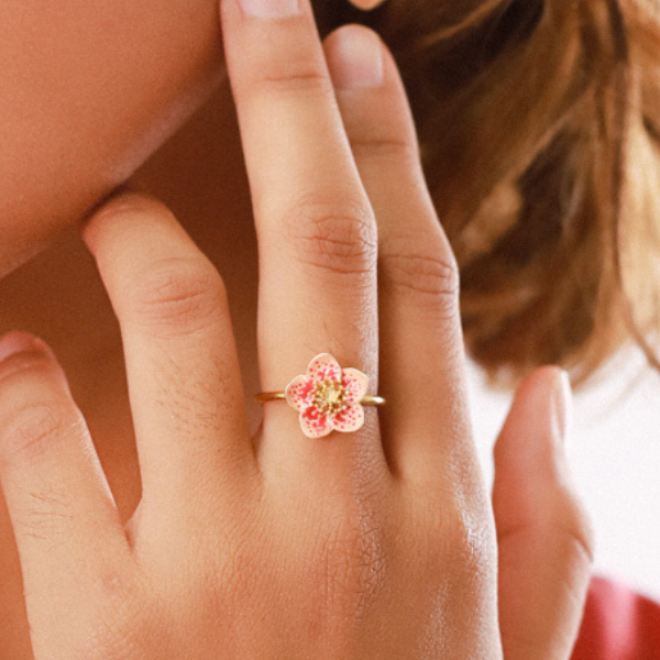 Image of model wearing pink and white hand painted flower ring on gold plated metal finish.