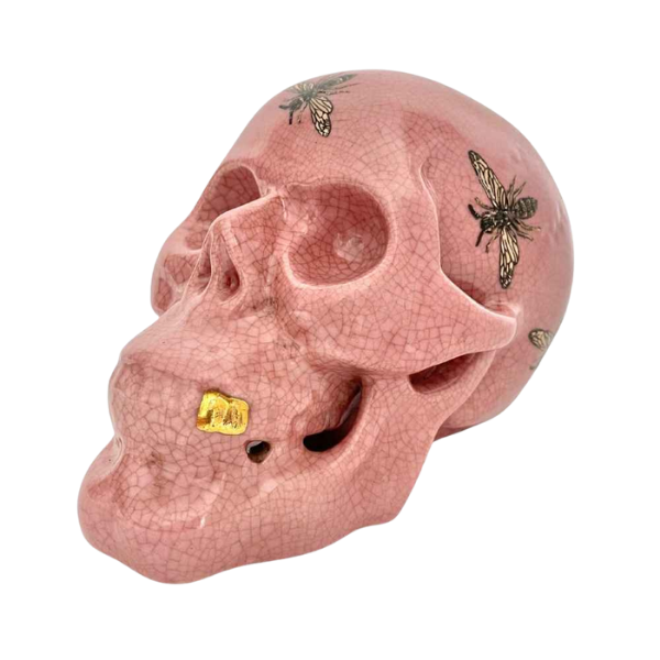 Image of pink ceramic human skull with bee pattern.