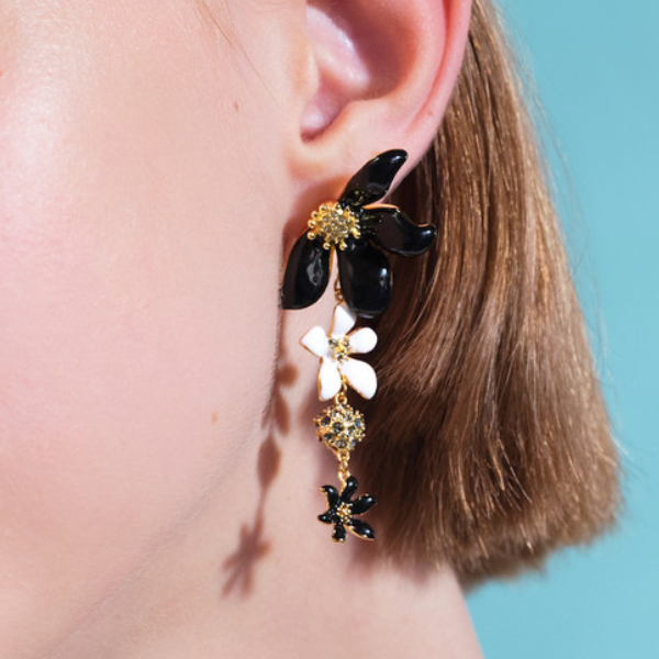Image of model wearing black and white flower earrings with 2 in 1 fastening system on gold finish.
