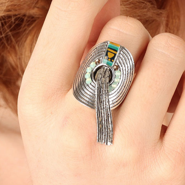 Image of model wearing tribal style silver folded disc ring embellished with gold, blue and turquoise beads, a hand painted motif and silver tassels.