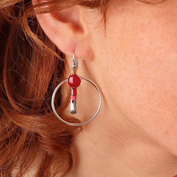 Image of model wearing cute ethnic style dangle hoop earrings hand painted in red shades with coloured precious stones and beads inside hoop on silver french hook.