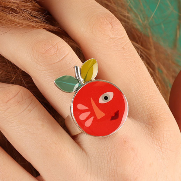 Image of model wearing quirky ring with a large happy orange face feature on silver metal finish.