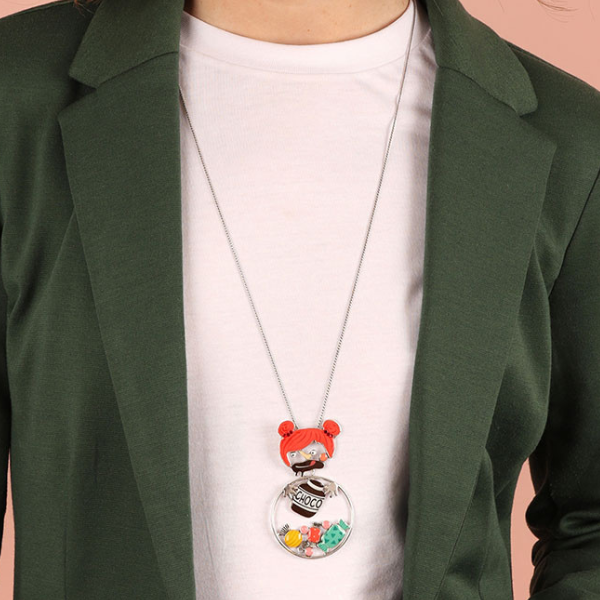 Image of model wearing quirky necklace featuring red headed girl eating chocolate all hand painted in multicoloured resin on silver plated finish.