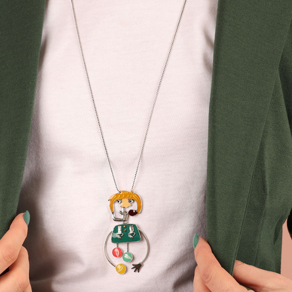 Image of model wearing quirky necklace featuring blonde headed boy with picking his nose, all hand painted in multicoloured resin on silver plated finish.