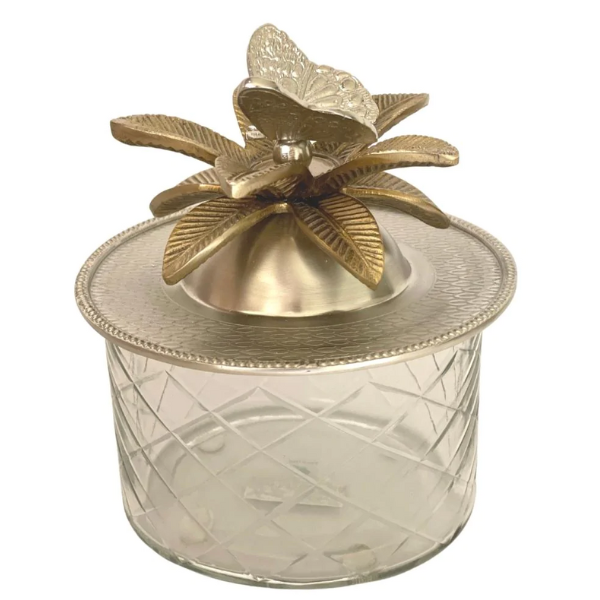 Image of round glass trinket box with brass lid that has butterfly handle surrounded by brass leaves.
