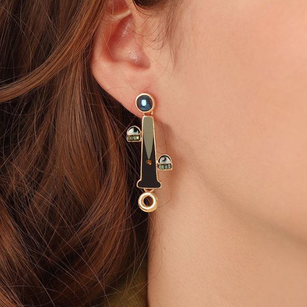 Image of model wearing long hand painted earrings with eyes and mouth features and blue stone bead at top.