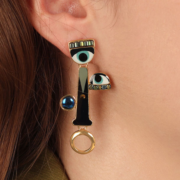Image of model wearing long hand painted earrings with eyes and mouth features and blue eye at top.