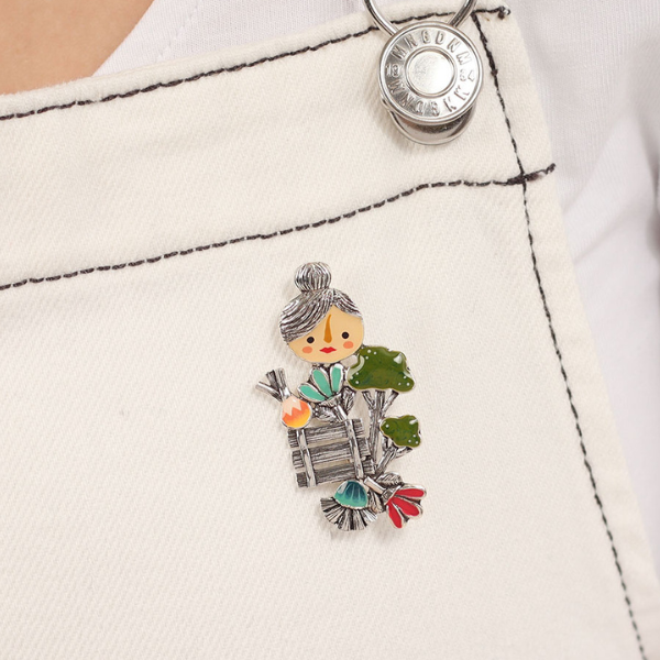 Image of model wearing brooch with character Josi Brocoli carrying market produce.