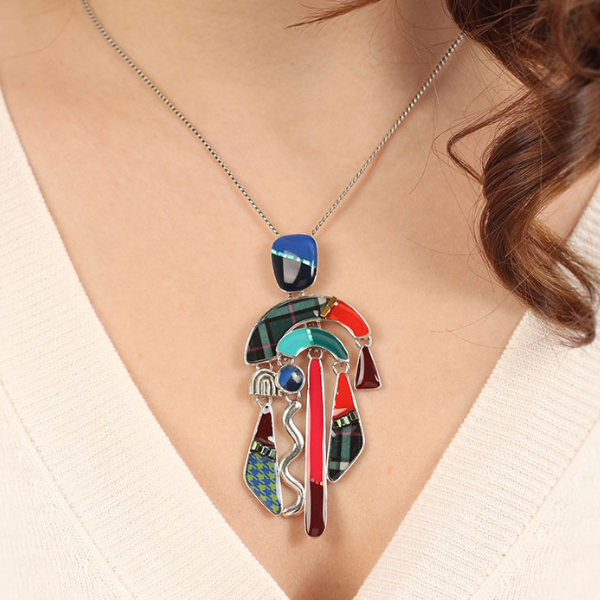 Image of model wearing striking multi coloured long necklace with many dangle shapes on silver metal chain.