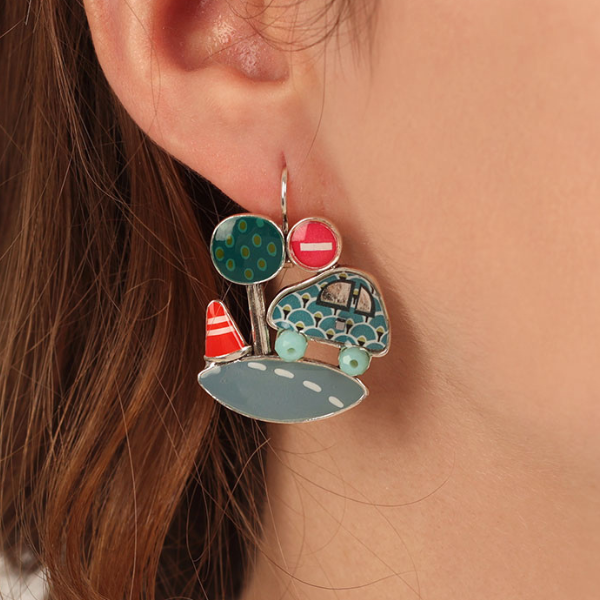 Image of model wearing earrings with car on a road with tree and cone hand painted as features.