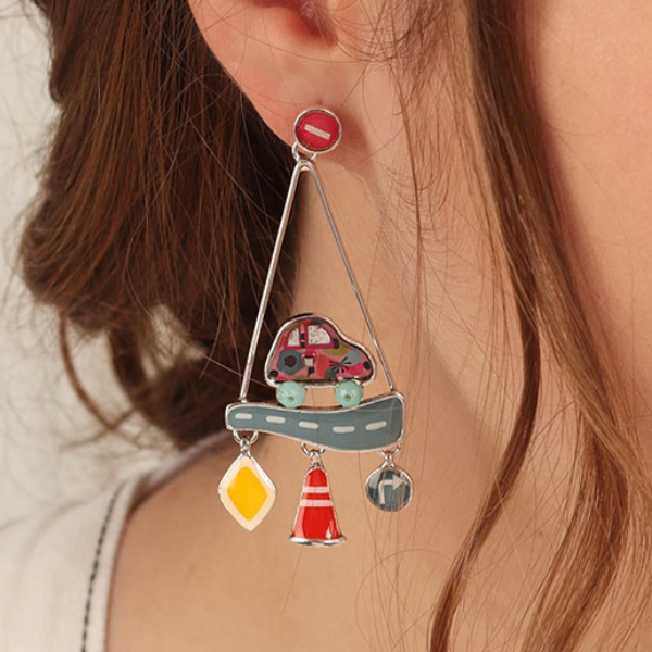 Image of model wearing hand painted car on road earrings inside triangle dangle with hazard sign features.