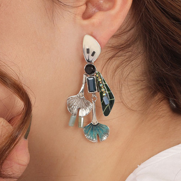Image of model wearing elegant earrings on stud encrusted with hand painted patterns and stones with blue tones.