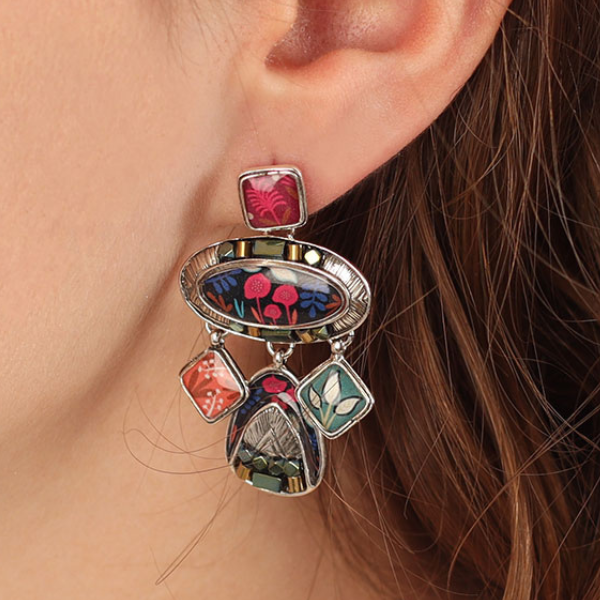 Image of model wearing dangle earrings encrusted with hand painted patterns and stones in multicolours.