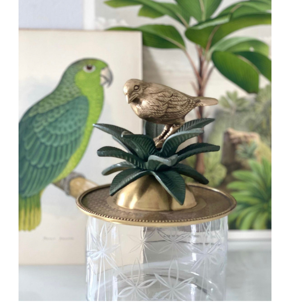 Image of classical trinket box that combines cut glass with brass.  Stunning brass lid with bird and verde coloured brass palm leaves sits atop a elegant cut glass container.  
