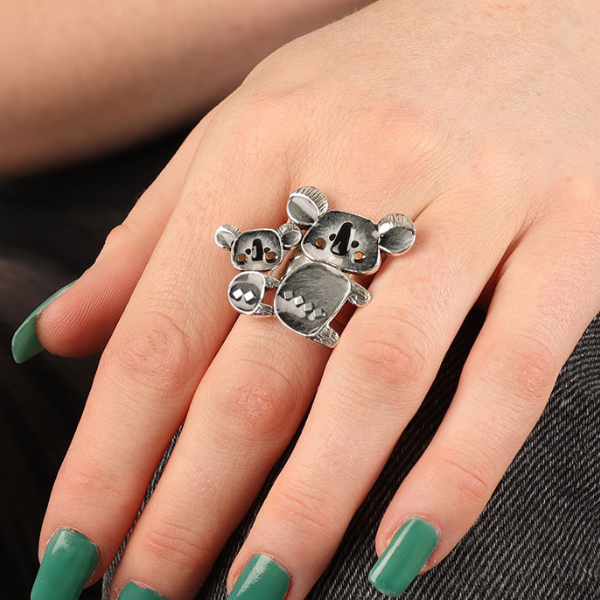 Image of model wearing cute koala ring with baby koala on its back on silver metal adjustable finish.