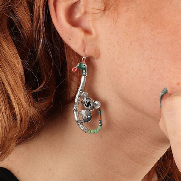 Image of model wearing cute quirky dangle earrings featuring a koala climbing on a snakes back on silver french hook.