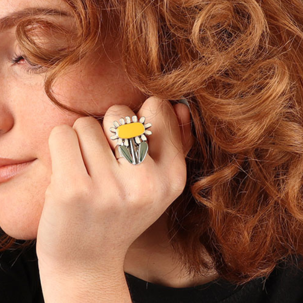 Image of model wearing bright pretty ring with yellow and white sunflower on silver metal adjustable band.