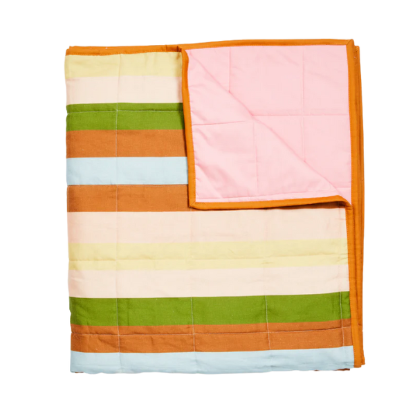 Image of linen quilted throw with multicoloured stripe print on pink background. Contrast cotton edging.