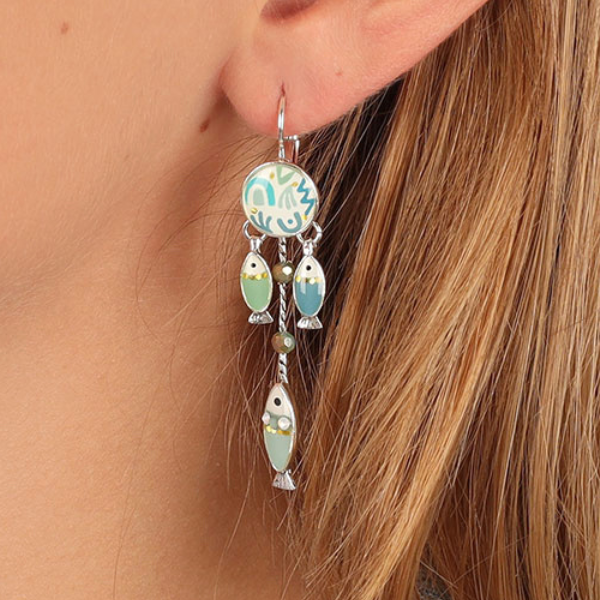 Image of model wearing fish dangle earrings hand painted in blue tones.
