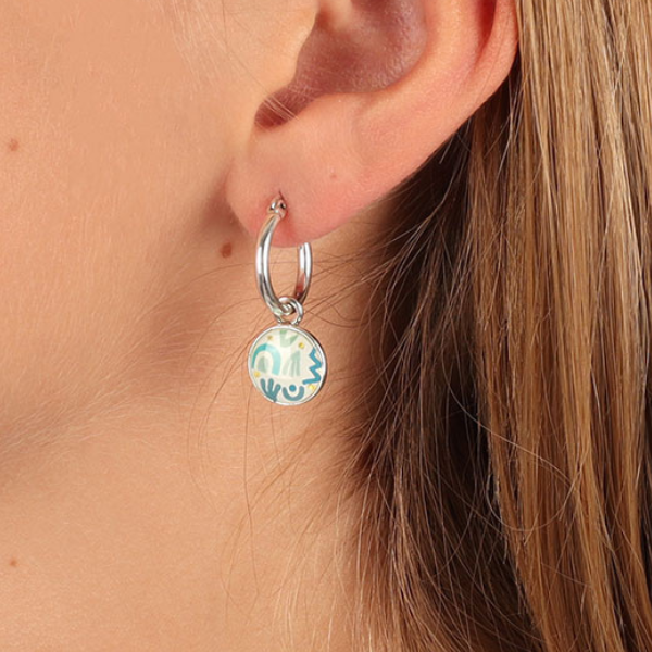 Image of model wearing dainty round earrings hand painted with blue patterns.
